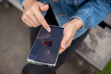 Chiang Mai, Tayland - 16 Sep 2024: Parkta dışarıda dinlenirken Shopee uygulamasını akıllı telefonunda kullanan bir kadın. çevrimiçi alışveriş uygulaması, e-ticaret, mobil uygulama, yaşam tarzları