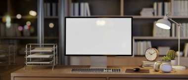 Beyaz ekran maketi ve aksesuarları olan bir bilgisayar, arka planda bir kitaplığı olan ve sıcak bir masa lambasıyla aydınlatılan bir odada, gece bir ahşap masanın üzerinde oturur. 3d görüntüleme, 3d illüstrasyon