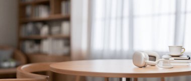 Konforlu, çağdaş bir evde yuvarlak ahşap bir masa, kulaklıklar, kahve fincanı, kitaplar ve masada sergilenen ürünler için bir fotokopi alanı. 3d görüntüleme, 3d illüstrasyon
