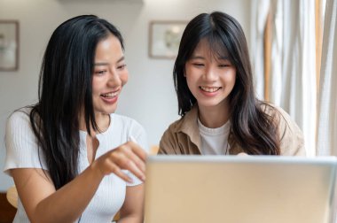 İki pozitif ve çekici Asyalı genç bayan arkadaş bir kafeden uzaktan birlikte çalışıyorlar, bilgisayar ekranına bakarken iş tartışıyorlar. üniversite öğrencileri, arkadaşlık, yaşam tarzları