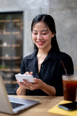 Çekici bir Asyalı iş kadını, bir kahve dükkanında uzaktan çalışıyor, işine odaklanmış, hesap makinesi kullanıyor. Ortak çalışma alanı, kablosuz teknoloji, yaşam tarzları