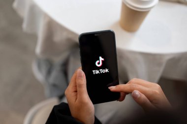 Chiang Mai, Tayland - Ekim 03 2024: Ekranda TikTok logosu olan iPhone tutan bir kadının yakın çekimi. Evde otururken akıllı telefonuyla TikTok kullanan bir kadın..
