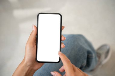 Kapalı mekanda oturan ve akıllı telefonunu kullanan beyaz ekran görüntülü bir kadının yakın plan fotoğrafı. İnsanlar ve kablosuz teknoloji kavramları