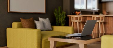 Çağdaş bir oturma odasındaki bir sehpada dizüstü bilgisayarın yakın plan dikiz görüntüsü. Dairesinde sarı bir kanepe ve açık bir mutfak alanı var. 3d görüntüleme, 3d illüstrasyon