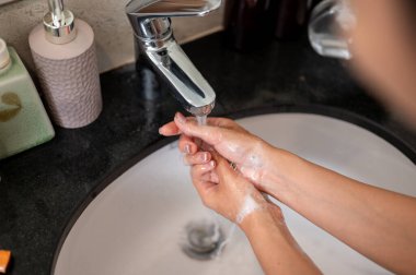 Ellerini banyo lavabosunda yıkayan ellerini sabunla ovuşturan bir kadının yakın çekimi. Hijyen, vücut bakımı, fotokopi alanı olan görüntü