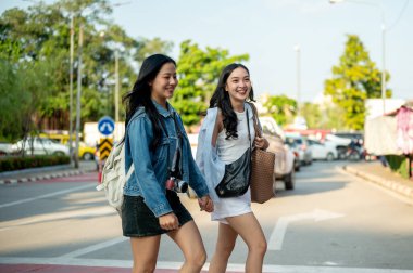 Güneşli bir günde Tayland 'da bir şehri gezerken birlikte yaya geçidinden geçen iki çekici, neşeli genç Asyalı kadın, şehri keşfetmekten zevk alır..