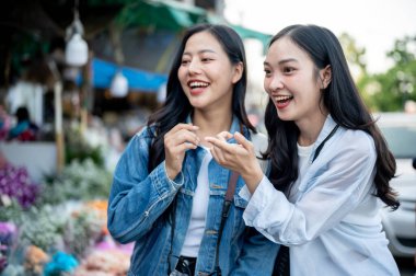İki neşeli Asyalı kadın Tayland 'da seyahat ederken çiçek pazarında birlikte çiçek seçip almaktan zevk alırlar. tatil, gezi, yaşam tarzları