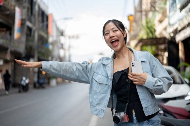 Kot ceketli neşeli, çekici bir Asyalı turist sokakta dikiliyor, taksiye biniyor ve Asya 'ya yaptığı gezinin tadını çıkarıyor. insanlar ve ulaşım kavramları