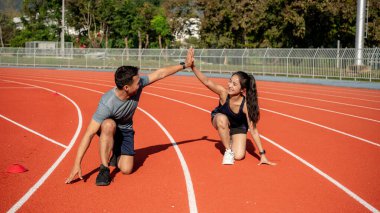 Güneşli bir günde bir stadyumda antrenman yapmaya hazırlanan iki Asyalı koşucu beşlik çakıyor. İnsanlar, dostluk ve spor kavramları