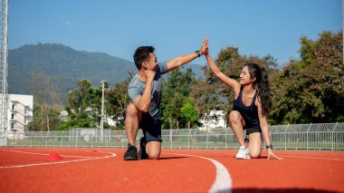 Güneşli bir günde bir stadyumda antrenman yapmaya hazırlanan iki Asyalı koşucu beşlik çakıyor. İnsanlar, dostluk ve spor kavramları