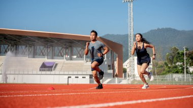 Güneşli bir günde stadyumda koşan iki kararlı Asyalı sporcu. rekabet, meydan okuma, spor oyunu, egzersiz, eğitim