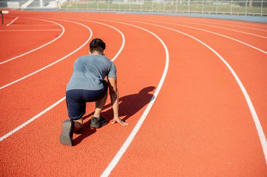Asyalı güçlü bir atletik erkek sporcu sabahleyin stadyumda antrenman yapıyor, koşmaya ve hazırlanmaya hazırlanıyor. bir arka plan resmi