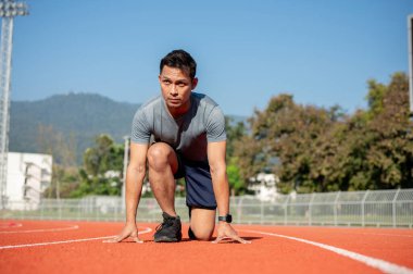 Güçlü, kararlı Asyalı atletik erkek sporcu sabahları stadyumda koşmaya ve hazırlanmaya hazırlanıyor..