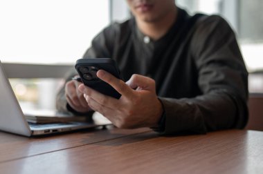 Ofisteki bir masada akıllı telefonunu kullanan bir iş adamının yakın çekimi. mesajları okumak, cevaplamak sohbet etmek, telefonda kaydırmak