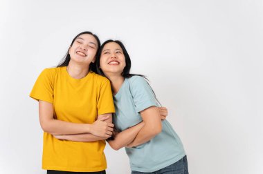 İki sevimli, gülümseyen Asyalı kadın beyaz bir stüdyonun arka planında sıradan giysiler içinde dikiliyorlar. en iyi arkadaş, arkadaşlık, ilişki, üniversite öğrencisi