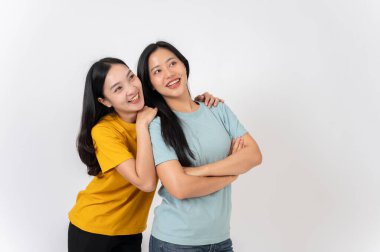 İki sevimli, gülümseyen Asyalı kadın beyaz bir stüdyonun arka planında dikilirken sarılıyorlar. en iyi arkadaş, arkadaşlık, ilişki, üniversite öğrencisi