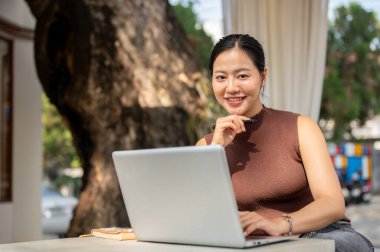 Güzel bir Asyalı kadın bir kafenin açık masasında dizüstü bilgisayarın önünde oturmuş kameraya gülümsüyordu. Kafeden, şehir hayatından, iş kadınından, serbest çalışanlardan.