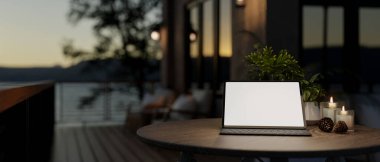 Beyaz ekran modeli olan dijital bir tablet ve karanlık çöktüğünde doğa manzaralı bir evin balkonundaki bir masada kablosuz bir klavye. 3d görüntüleme, 3d illüstrasyon