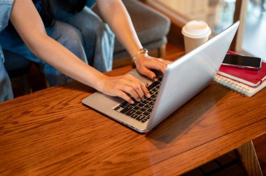 Laptopçu dükkanında uzaktan kumandayla çalışan, parmaklarını dizüstü bilgisayarında yazan bir kadının yakın çekimi. insanlar ve teknoloji kavramları
