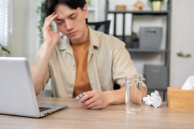 Hasta, bitkin, Asyalı bir işadamı elinde bir paket hapla ofisinde oturuyor, çalışırken baş ağrısı ya da migrenle boğuşuyor. Sağlık, hastalık