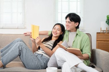 Mutlu, samimi, genç Asyalı evli bir çift evde birlikte harika vakit geçirir, sabahları kanepede kitap okurlar. Yeni evli çift, sağlıklı ilişki, kaynaşma, kaygısız