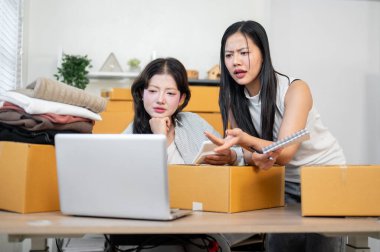 İki ciddi, stresli Asyalı kadın envanter çalışanı, web sitesindeki siparişleri kontrol ettikten sonra, ofiste birlikte çalıştıktan sonra stok ürünlerinin eksikliğinden endişe duyuyorlar..