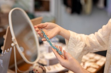 Güzel mavi bir bilezik tutan, moda mağazasından almak için eşyalar seçen bir bayan müşterinin yakın çekimi. Alışveriş, yaşam tarzı, tüketim