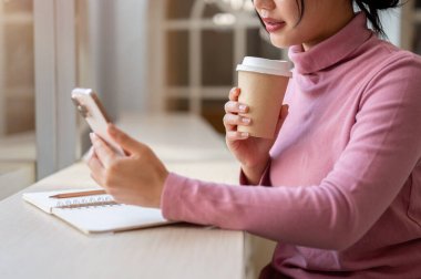 Bir kafede dinlenirken akıllı telefonuyla mesaj okuyan düşünceli Asyalı bir kadının yakın çekimi. İnsanlar ve teknoloji