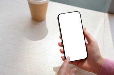 Parlak bir günde bir kafede akıllı telefonunu kullanan bir kadının yakın plan fotoğrafı. Beyaz ekran maketli akıllı telefon. insanlar ve teknoloji kavramları