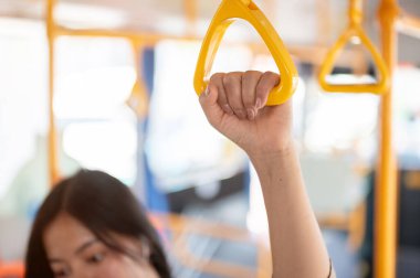 Şehirdeki bir otobüste gidip gelirken tırabzan tutan bir kadının yakın çekimi. insanlar ve ulaşım kavramları