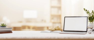 Minimalist bir odanın bulanık arka planına sahip beyaz ekranlı bir dizüstü bilgisayar ve dekoratif öğeler. 3d görüntüleme, 3d illüstrasyon