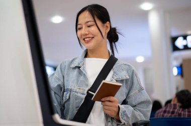 Güzel, gülümseyen Asyalı bir kadın havaalanındaki bir gişede uçuşu için kayıt yaptırıyor. Tatilde seyahat etmekten mutlu. seyahat, tatil, ulaşım