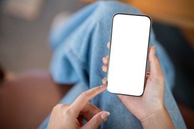 Evin içinde otururken akıllı telefon kullanan bir kadının yakın çekim görüntüsü. Beyaz ekran maketli akıllı telefon. İnsanlar, yaşam tarzı, kablosuz teknoloji