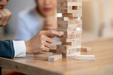 Oturma odasındaki kahve masasında arkadaşlarıyla Jenga oynarken bir adamın parmaklarının dikkatlice tahta bloğu kaldırması. Oyun masası, keyif, eğlence etkinliği