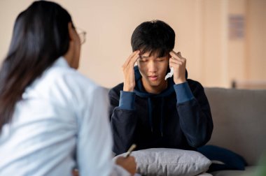 Stresli, ağlayan Asyalı genç bir adam klinikte psikoloğuyla konuşuyor, sağlık kontrolü sırasında ruhsal bir çöküntü yaşıyor. ruh sağlığı kavramı