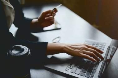 Kredi kartı tutan ve ofisteki bir masada dizüstü bilgisayara yazı yazan bir iş kadınının yakın çekimi kredi kartını bir web sitesine kaydettirir. Bankacılık, ödeme, nakit para, para