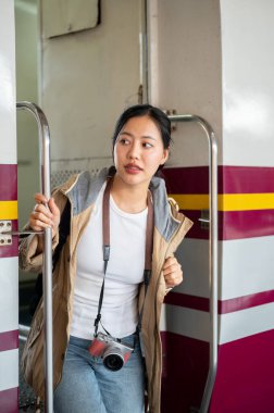 Güzel Asyalı kadın tren istasyonunda arabadan inerken etrafına bakıyor. Klasik tren istasyonu ya da tren istasyonu.