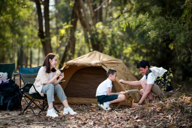 Anne oturup oğlunun babasından nasıl kamp çadırı kurulacağını öğrenmesini izliyor. Aile gezisi, orman kampı, açık hava aktiviteleri..
