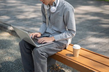 Asyalı bir adamın dizüstü bilgisayarında yazarken ya da sohbet ederken, kaldırım kenarında otururken. Boş zaman geçirmek, çalışmak ya da dışarıda çalışmak..