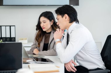 Erkek ofis çalışanı kadın iş arkadaşının dizüstü bilgisayarına bakıyor. İş adamı ve iş kadını ofiste tartışıyorlar..