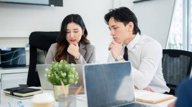 Erkek ofis çalışanı, kadın iş arkadaşının dizüstü bilgisayarına dikkatle bakıyor. İş adamı ve iş kadını ofiste tartışıyorlar..
