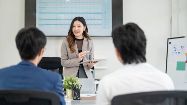 Kadın ofis çalışanı, erkek iş arkadaşıyla konuşurken dijital tablet tutuyor. İş adamı ve kadın ofiste toplantı yapıyorlar..