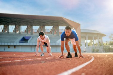 Yarış pistinde koşmaya hazır iki Asyalı adam. Spor ya da spor, spor, spor ve sağlık..