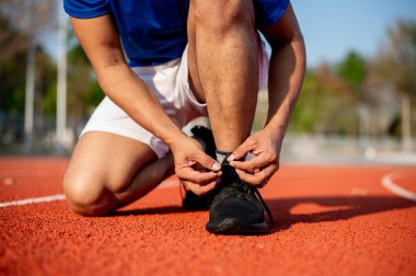 Siyah spor ayakkabı bağcığını hipodromda bağlarken çömelmiş bir adama yaklaş. Spor ya da spor, spor, spor ve sağlık..