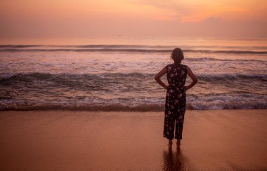 Girl watching the sunrise in Mahabalipuram Beach, Tamil Nadu, India. Focus set on the girl.