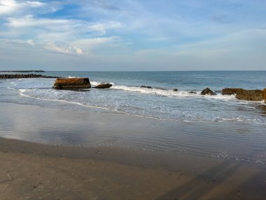 The evening sun sets over Tharangambadi beach in Tamil Nadu, across the calm waters of the Bay of Bengal along this peaceful shoreline.