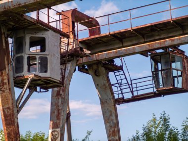Demiryolu raylarında paslanmış endüstriyel vinç. Terk edilmiş endüstriyel tesis kavramı. İflas etmiş ve kullanılmamış bir şirket, hurda bir metal yığını.