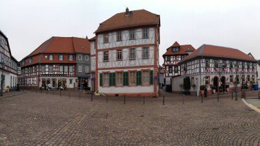 Traditional timber-framed houses lining Freihofplatz, main town square in historic center of the town, early evening view, panoramic shot, Seligenstadt, Germany - January 25, 2023