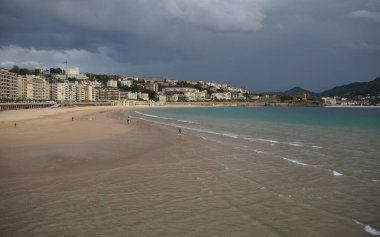 Şehrin kıyı şeridi, La Concha Körfezi 'nin kumlu plajı, arka planda fırtınalı bulutlar, Donostia-San Sebastian, Bask Ülkesi, İspanya - 12 Mayıs 2017