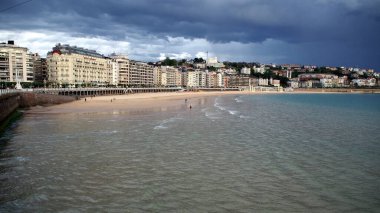 Şehrin kıyı şeridi, La Concha Körfezi 'nin kumlu plajı, arka planda fırtınalı bulutlar, Donostia-San Sebastian, Bask Ülkesi, İspanya - 12 Mayıs 2017